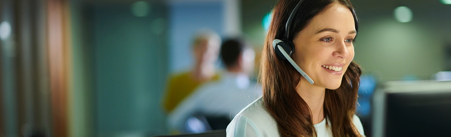 Woman in office smiling and wearing headset