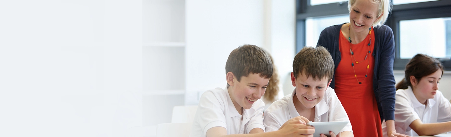 A classroom with a teacher and school children using a tablet device