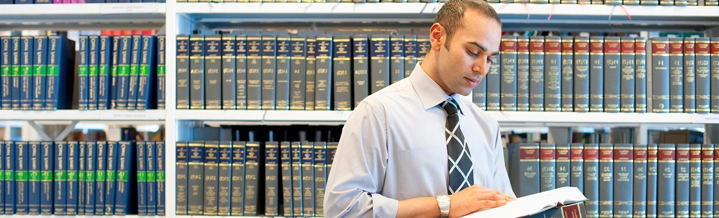 Man on front of book shelves and reading a book