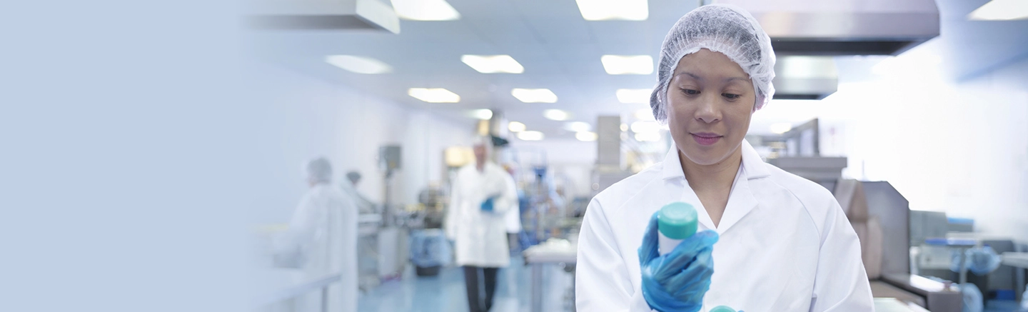 Woman wearing lab coat and holding a container