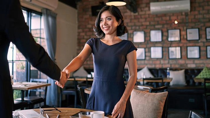 Woman in blue dress shaking hands man