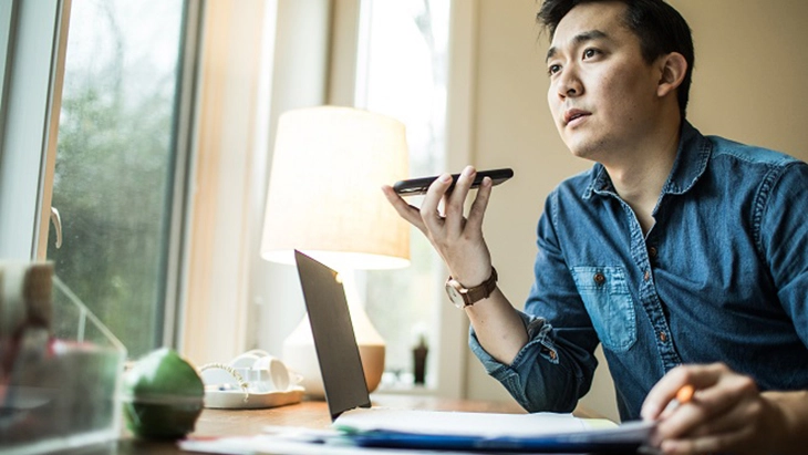 Man speaking on a phone while working at a desk