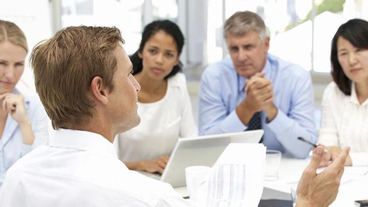 Man in office talking to four work colleagues