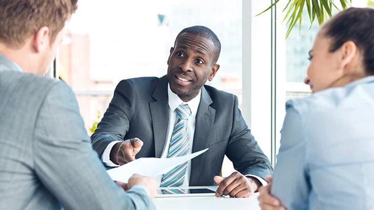 Man in business suit in discussion with two other people