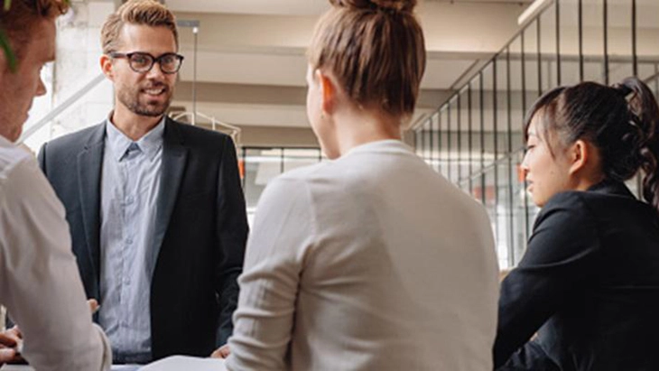 Man with glasses talking to three colleagues