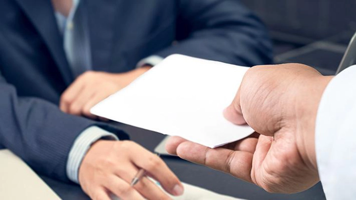 Hand handing slip of paper to another set of hands