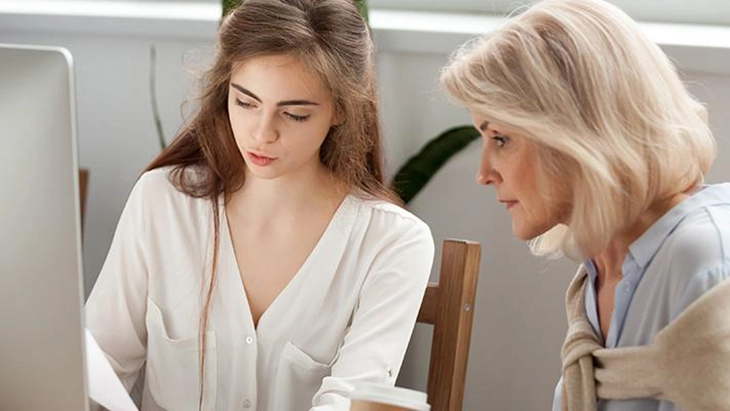 Older woman instructing younger woman in office space