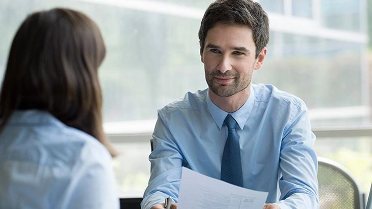 Man holding sheet of paper and interviewing a woman