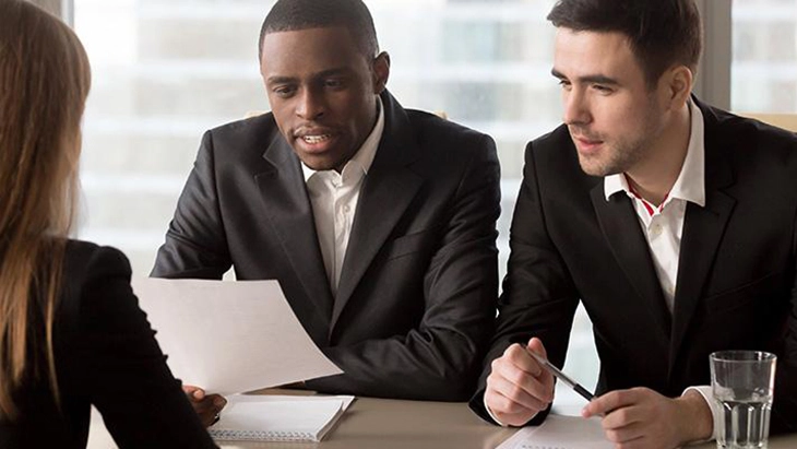 Two men interviewing a women