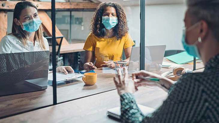 Women wearing safety masks in interview with a screen divider on the table