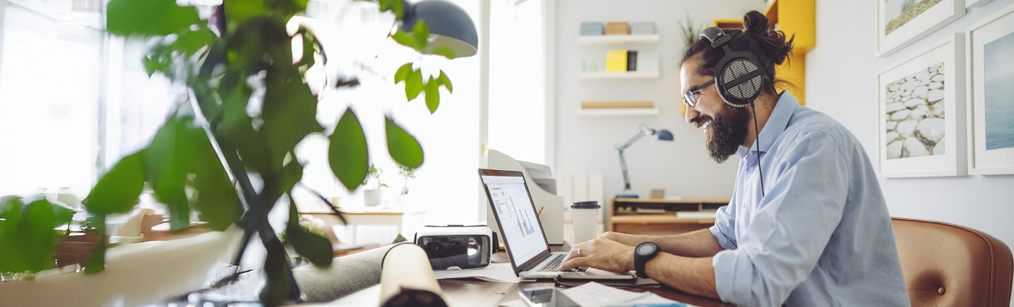 Jobseeker working on a CV at a desk using a laptop in a home office setting.