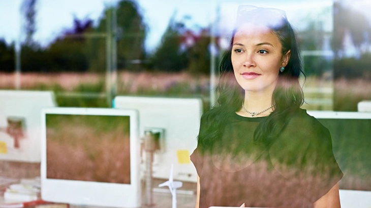 Young woman in work space next to computer looking ahead