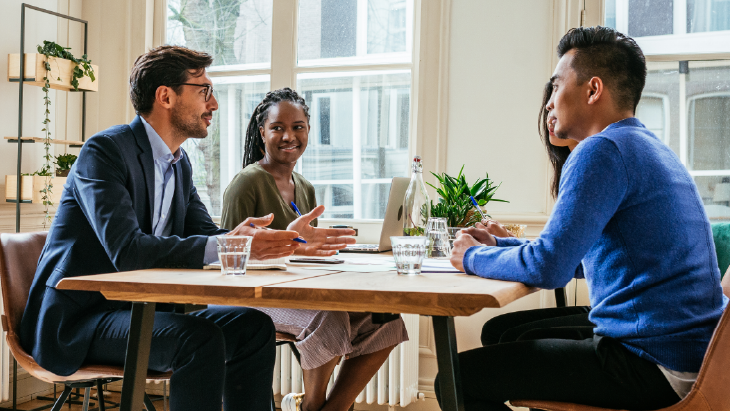Professionals in discussion around a table in a modern office, illustrating collaborative finance recruitment planning.