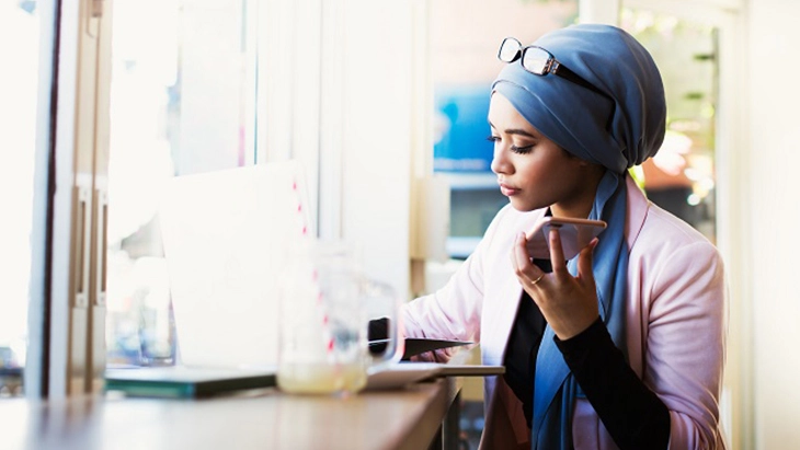 Woman working at desk and holding mobile phone