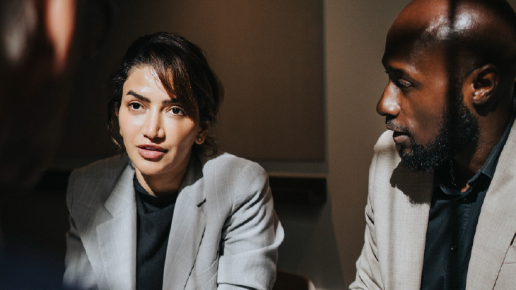 Two professionals in discussion in a formal meeting setting, illustrating executive leadership engagement.