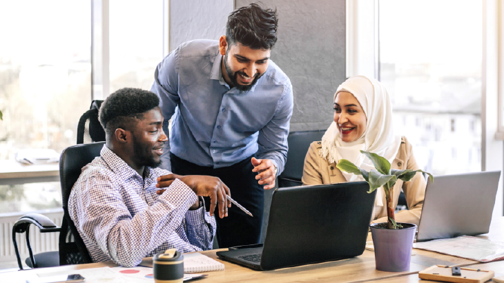Finance professionals collaborating at laptops in a modern office, representing the development of a finance centre of excellence to support business transformation.