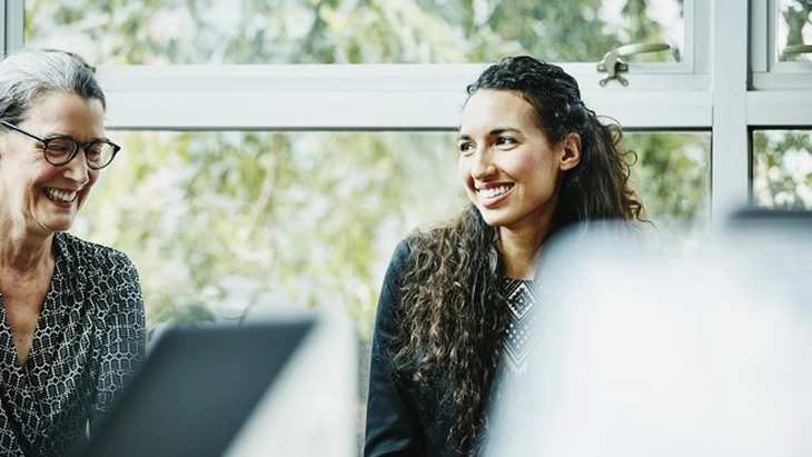 Two women in work space smiling