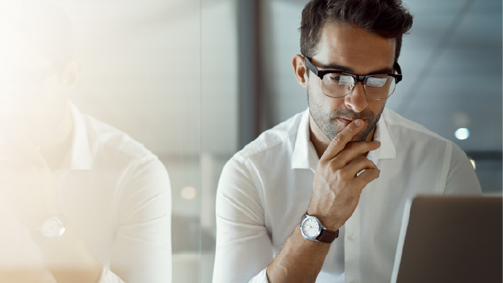 Man with glasses studying a sheet of paper
