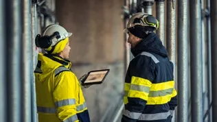 Engineers reviewing digital plans on a live infrastructure site, representing scalable workforce delivery and operational collaboration for Amey.